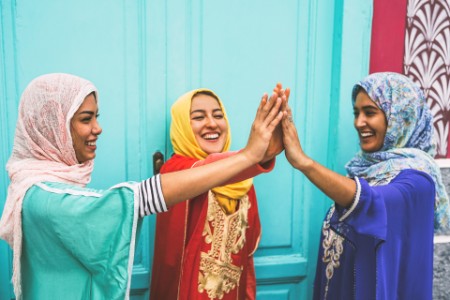 Three muslim women holding hands and smiling