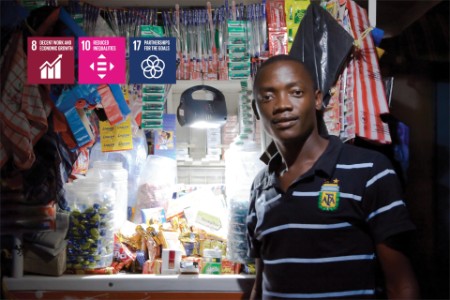 Man poseert in zijn winkel met een schijnwerper in Tanzania