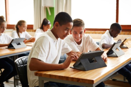 School students looking on tablet in classroom
