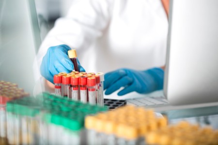 Close-up of lab technician examining test tubes in laboratory