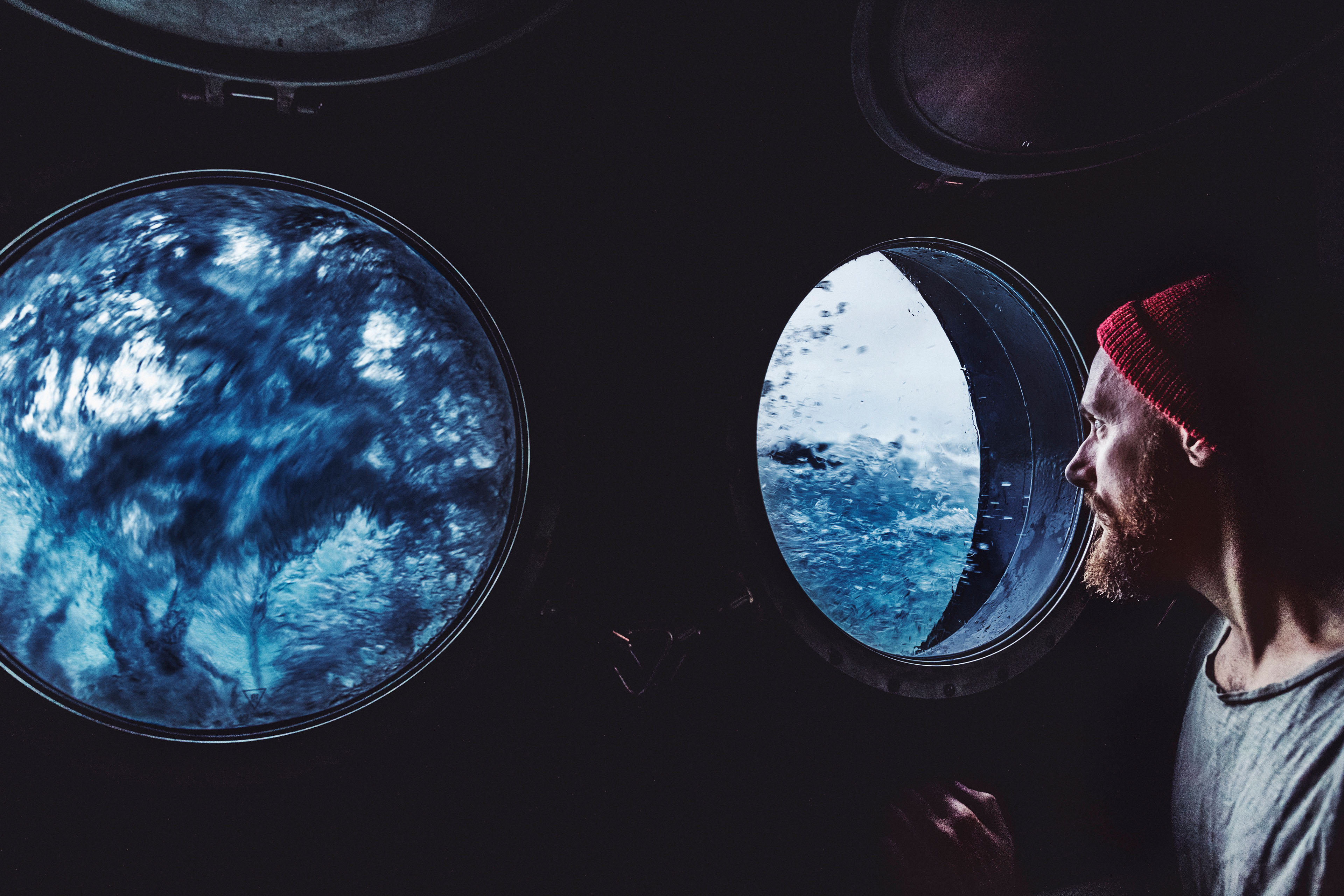 Man at the porthole of a vessel in a rough sea