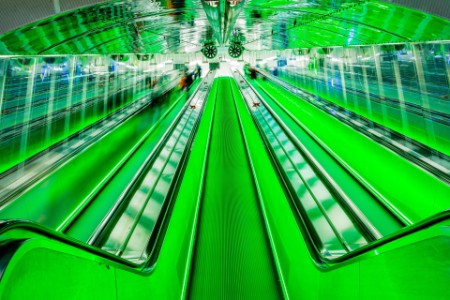 Movimiento borroso de una escalera mecánica iluminada en verde