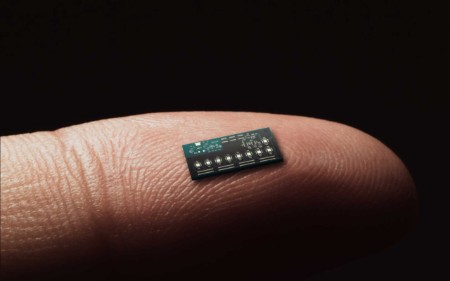 Grande plano do dedo segurando um pequeno chip de computador