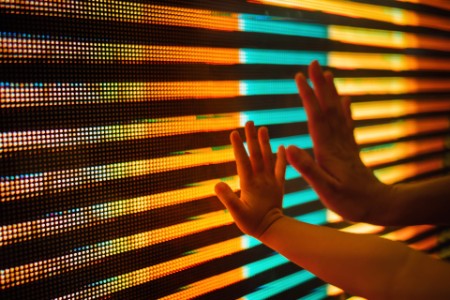 母亲和孩子用手触摸发光的多色LED显示屏的特写