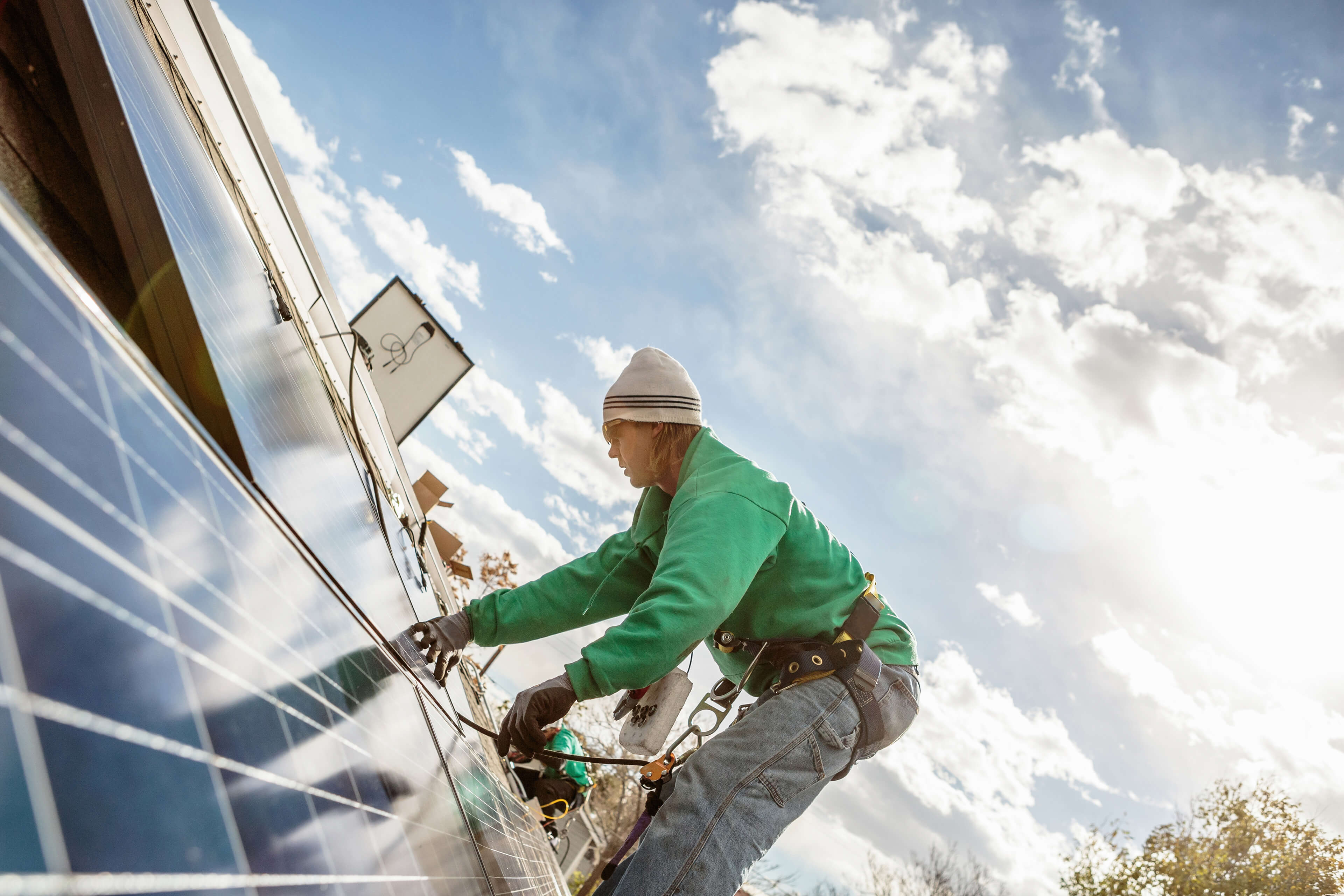 
            Mitglied des Bauteams, das ein Solarpaneel auf einem Hausbild installiert
        