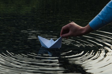Person holding paper boat in Lake