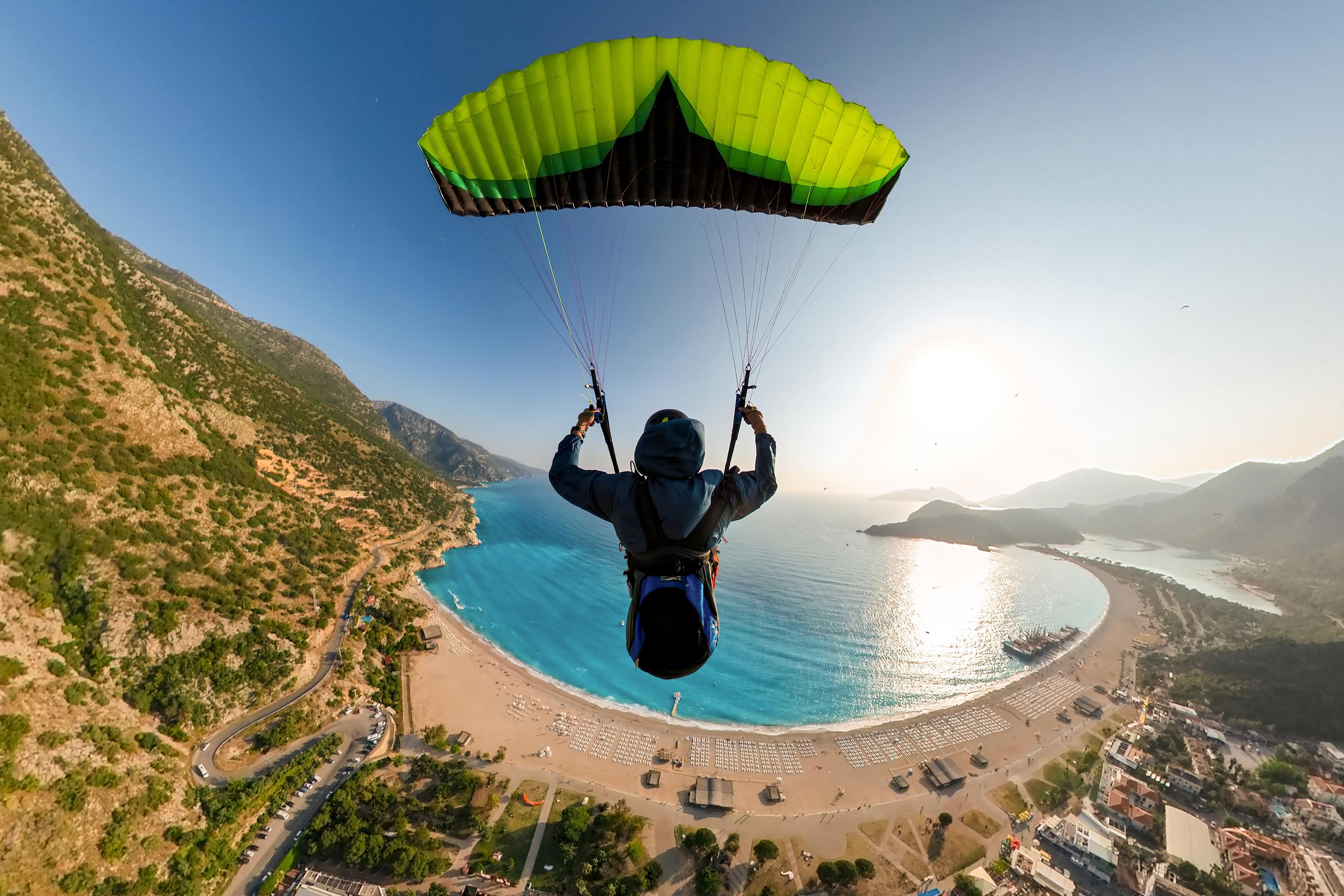Extreme paraglider pilot flying over the beach