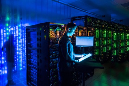 Man using digital tablet in dark server room