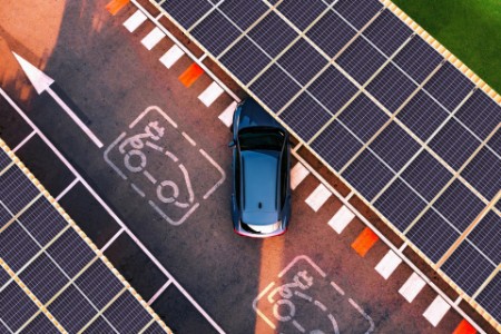 Aerial view of electric car parking in charging station with solar panels