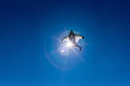 aerial view of flying white wingsuit with sunflare