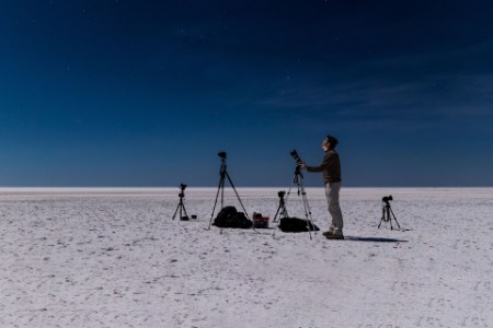 Man in desert photographing the night sky