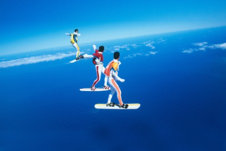 Three people skyboarding against blue sky