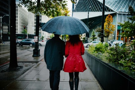 Couple walking under umbrella on city street