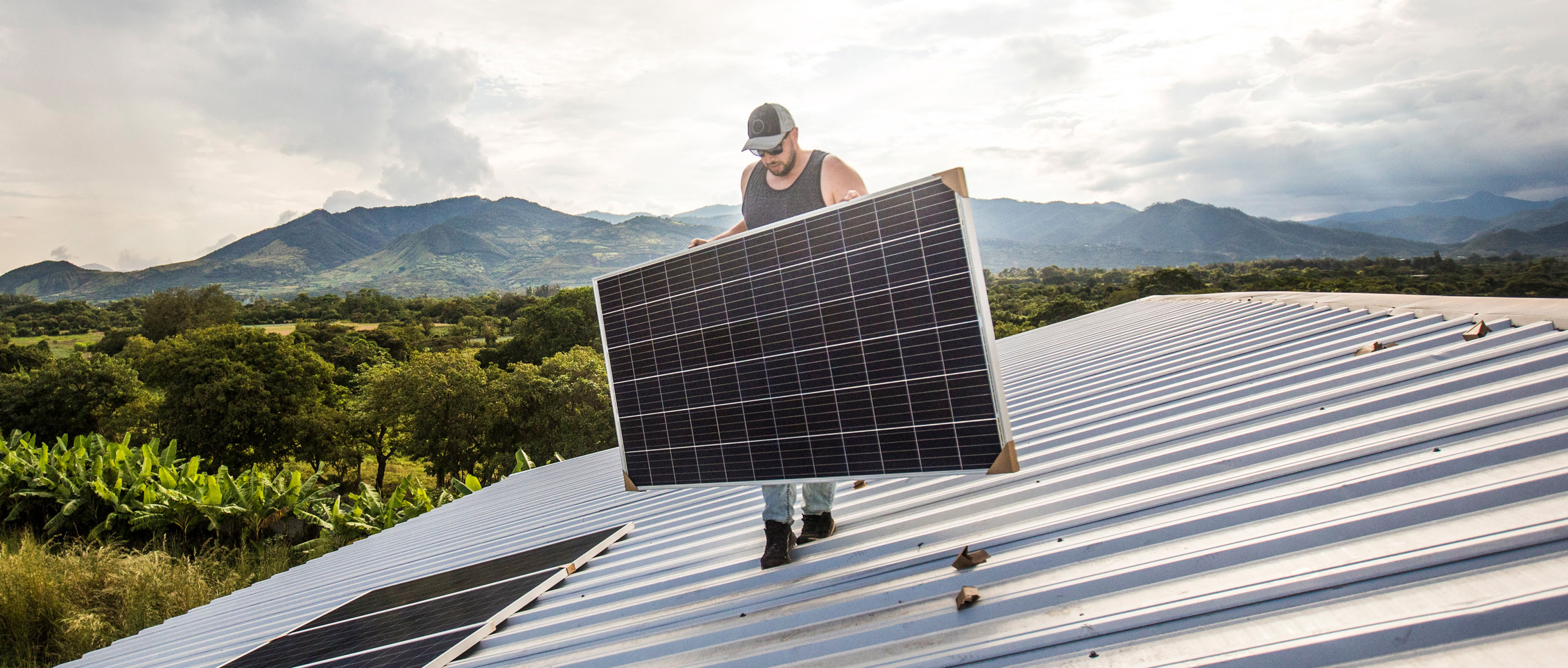 Hombre llevando un panel solar en el techo durante la instalación