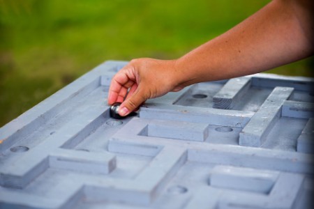 close up of hand placing marble into wooden maze game hero image