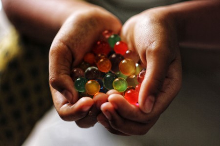 cropped hands of person holding colored marbles
