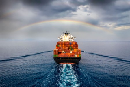 rainbow over a container ship at sea