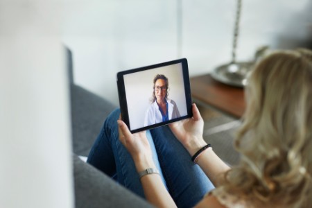 Young woman having online meeting with female healthcare person
