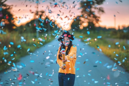 woman with colorful confetti standing road sunset