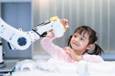 asian little girl touching a robotic machine arm