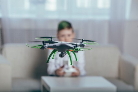Boy flying drone in living room at home