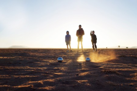 Pétanque Boules Game being played by three boys in the desert at sunrise