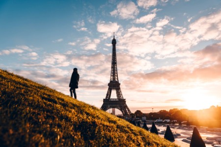 
            Une femme sur une colline herbeuse regarde la Tour Eiffel
        