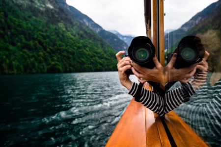 Woman taking photograph with camera from a boat window on a river