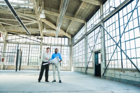Businessmen blueprints empty warehouse