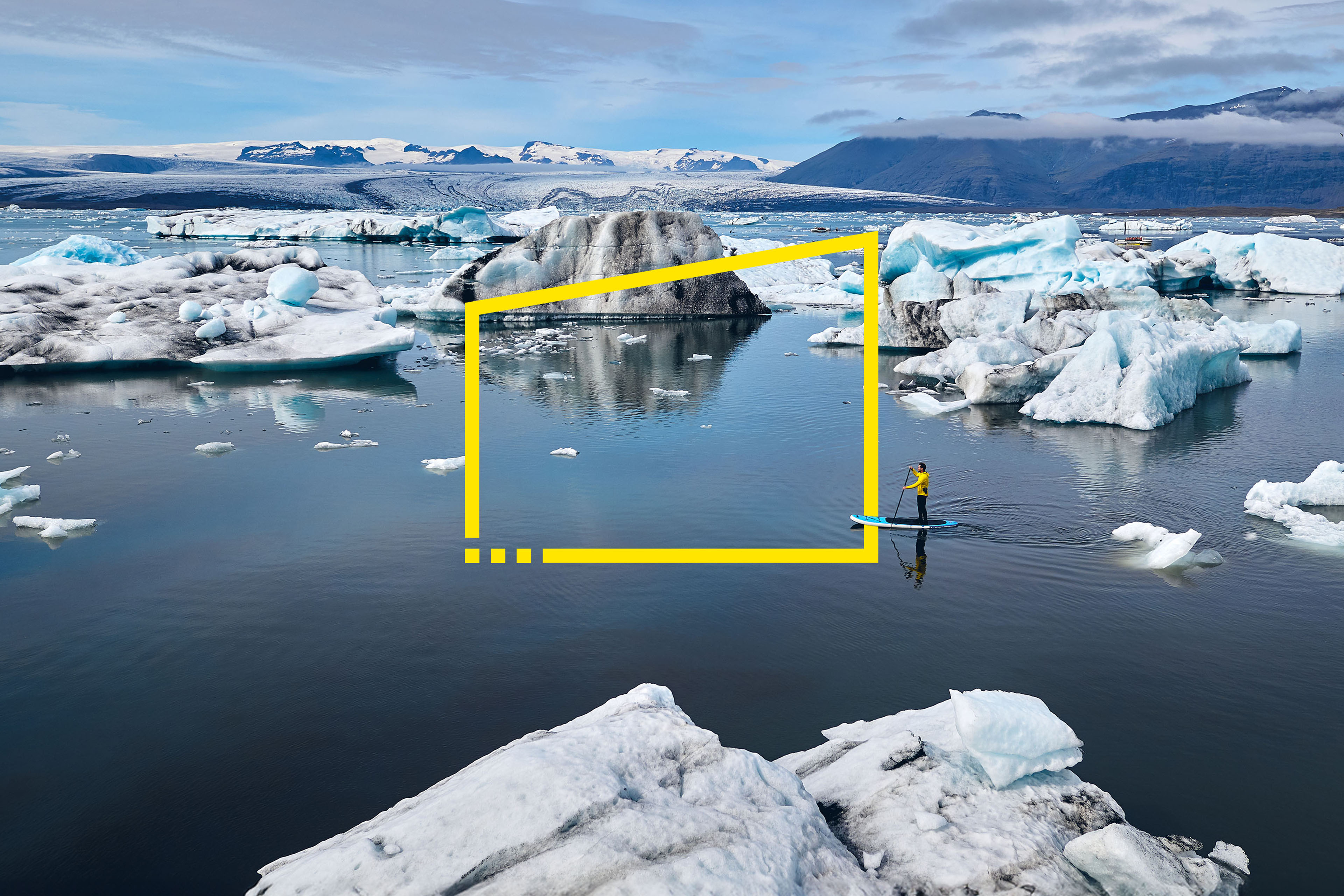 Hombre de pie en una tabla remando a través de una laguna glaciar en Islandia