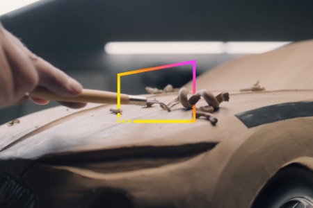 Man with rake working on clay car model