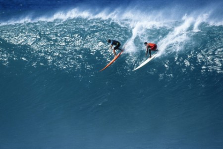 Two surfers surfing in huge wave
