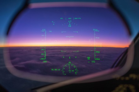 Boeing 787 cockpit window view at sunrise above the clouds