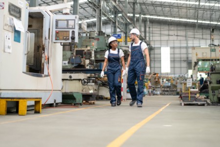 Dois engenheiros conversam enquanto caminham por uma fábrica automatizada