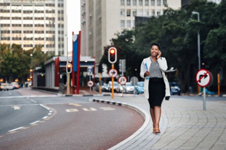 Smiling businesswoman walking while talking on mobile phone