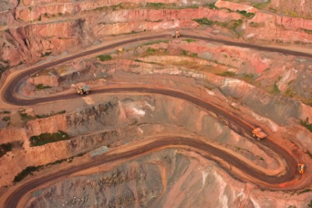 Tipper trucks carry iron ore up the side of an open cast mine