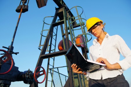 Инженер делает записи в блокноте на нефтяном месторождении
