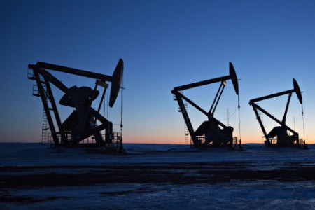 The silhouettes of pumpjacks are seen above oil wells