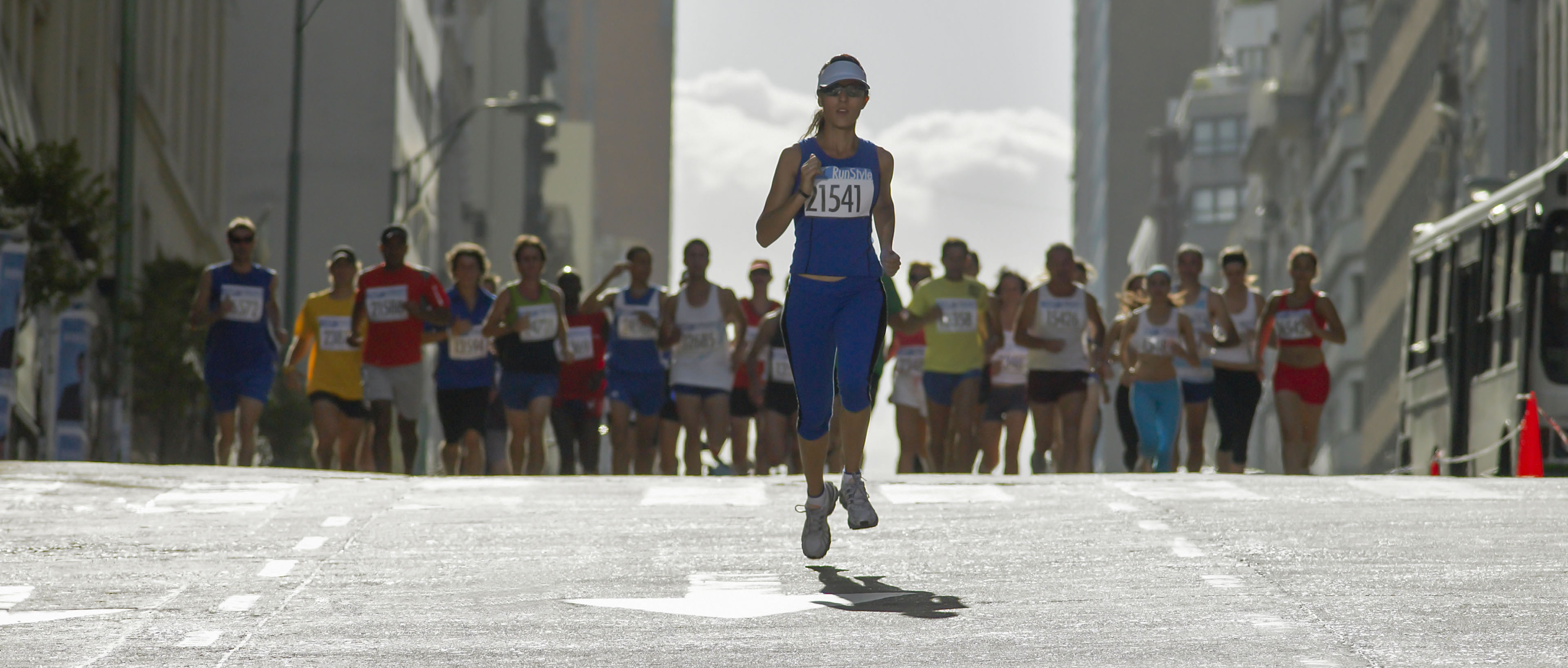 Mujer corriendo frente a grupo en una maratón