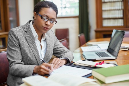 Woman lawyer sits at desk working with papers and a laptop