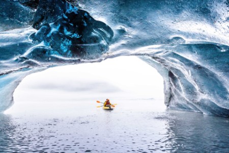 Tourists kayaking blue ice cave Alaska