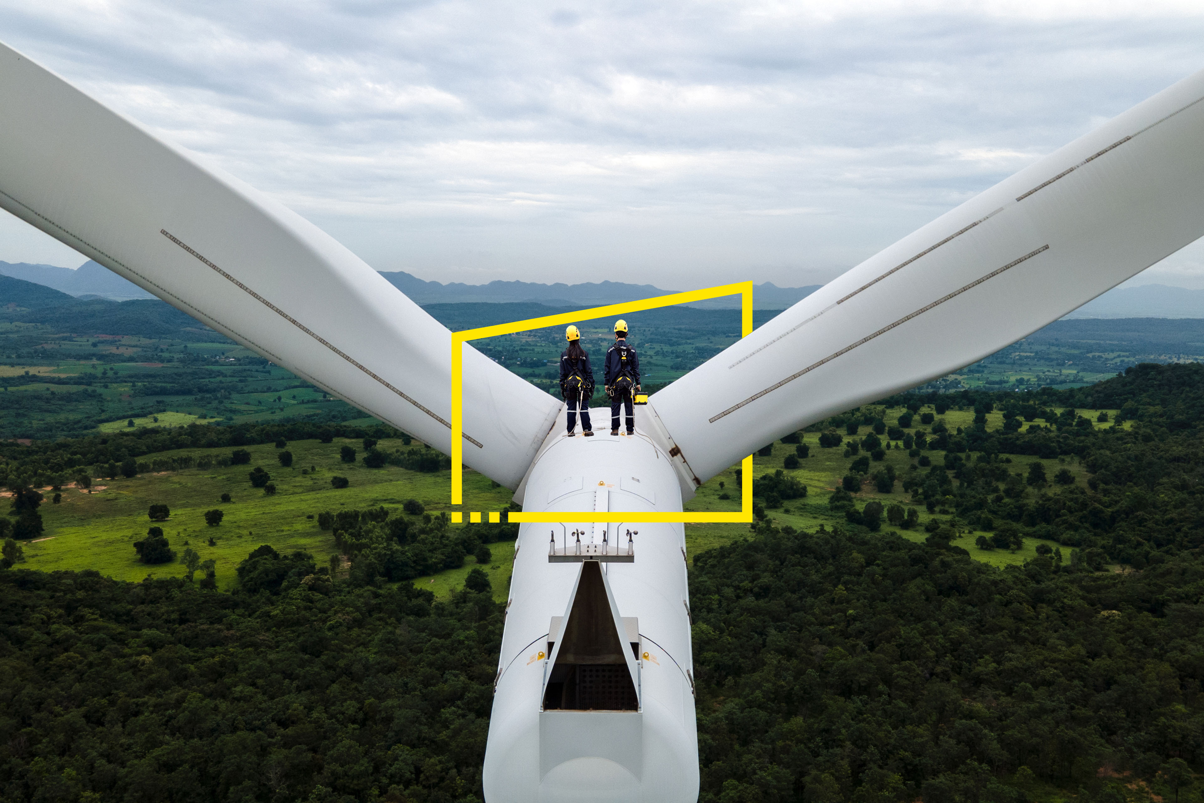 Two engineers working on top of wind turbine background
