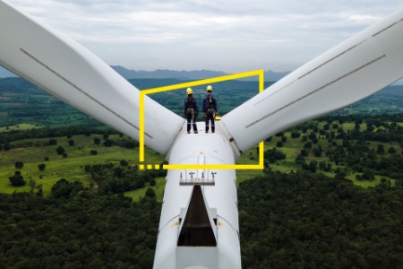 two engineers working on top of wind turbine background