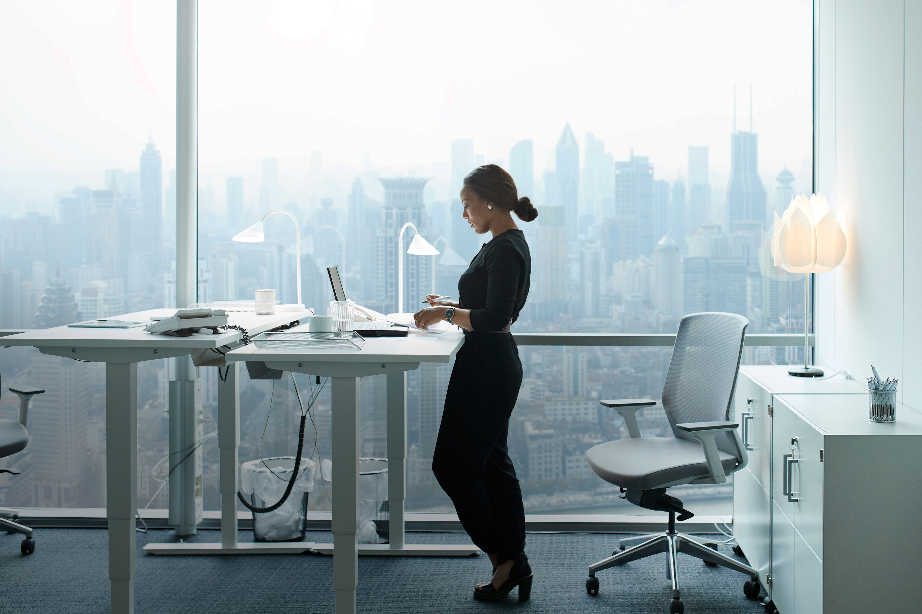 Businesswoman working on computer in office with beautiful view of skyline