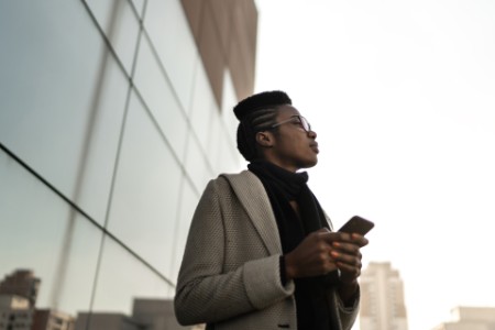 Young businesswoman using mobile phone and looking away at office rooftop