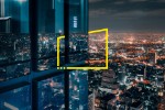 Janela de vidro para escritório acima de uma cidade brilhante à noite