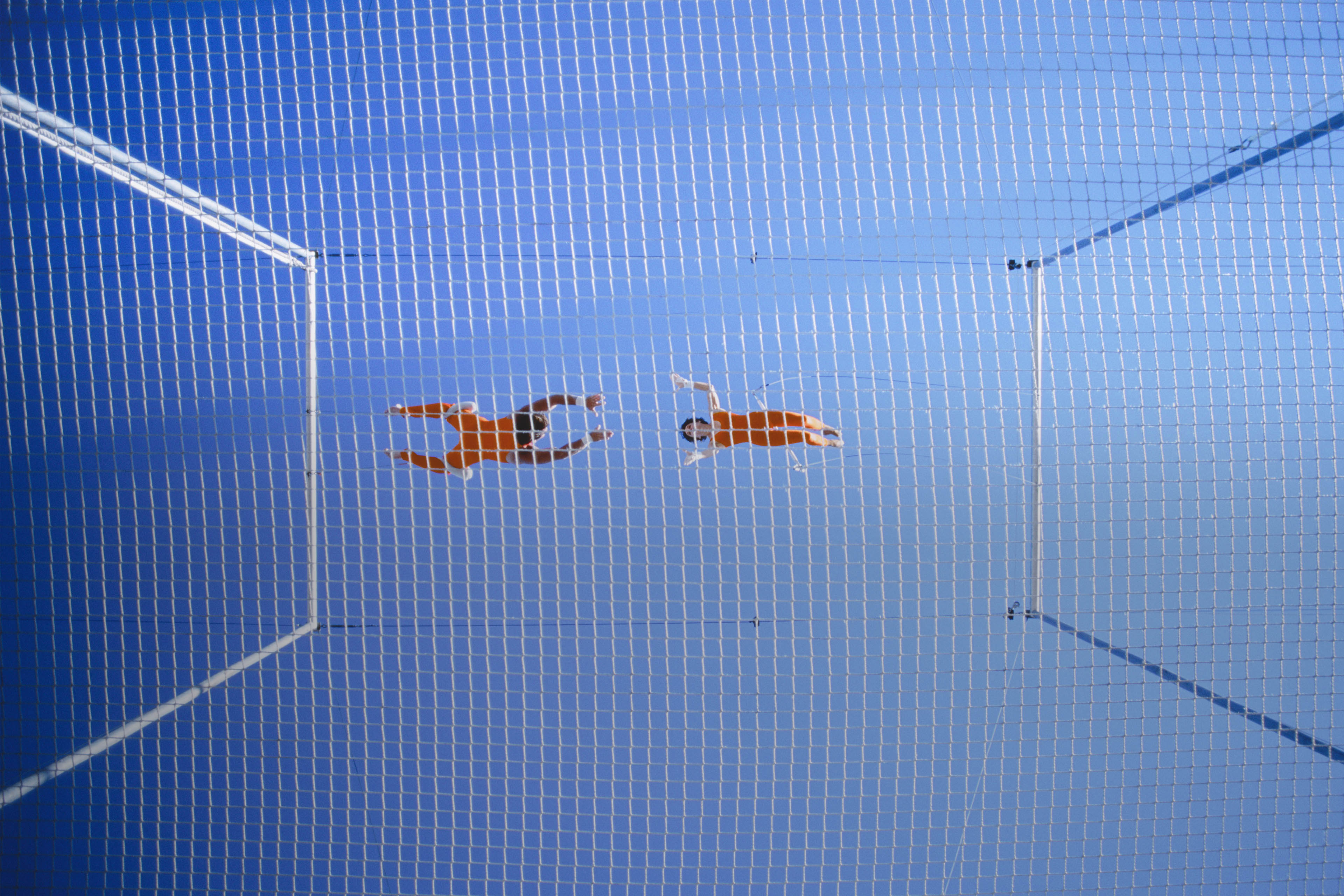 Two trapeze artists performing release move