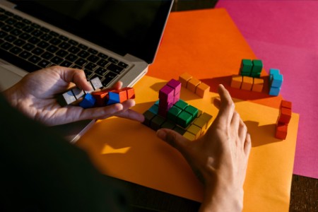 Hands of businesswoman playing with colorful toy blocks by laptop at table