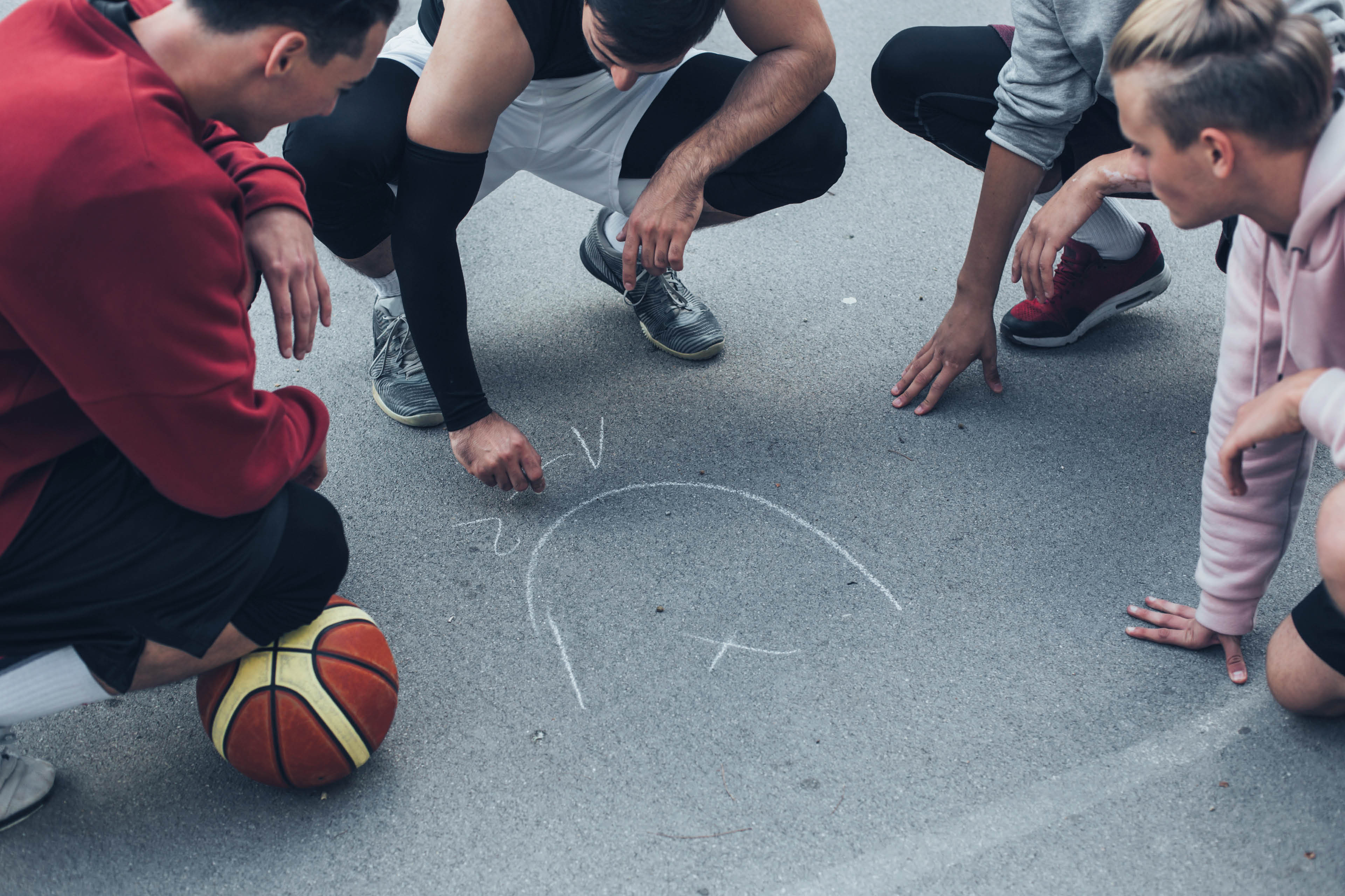 Jóvenes trazando jugada de basquet en el piso