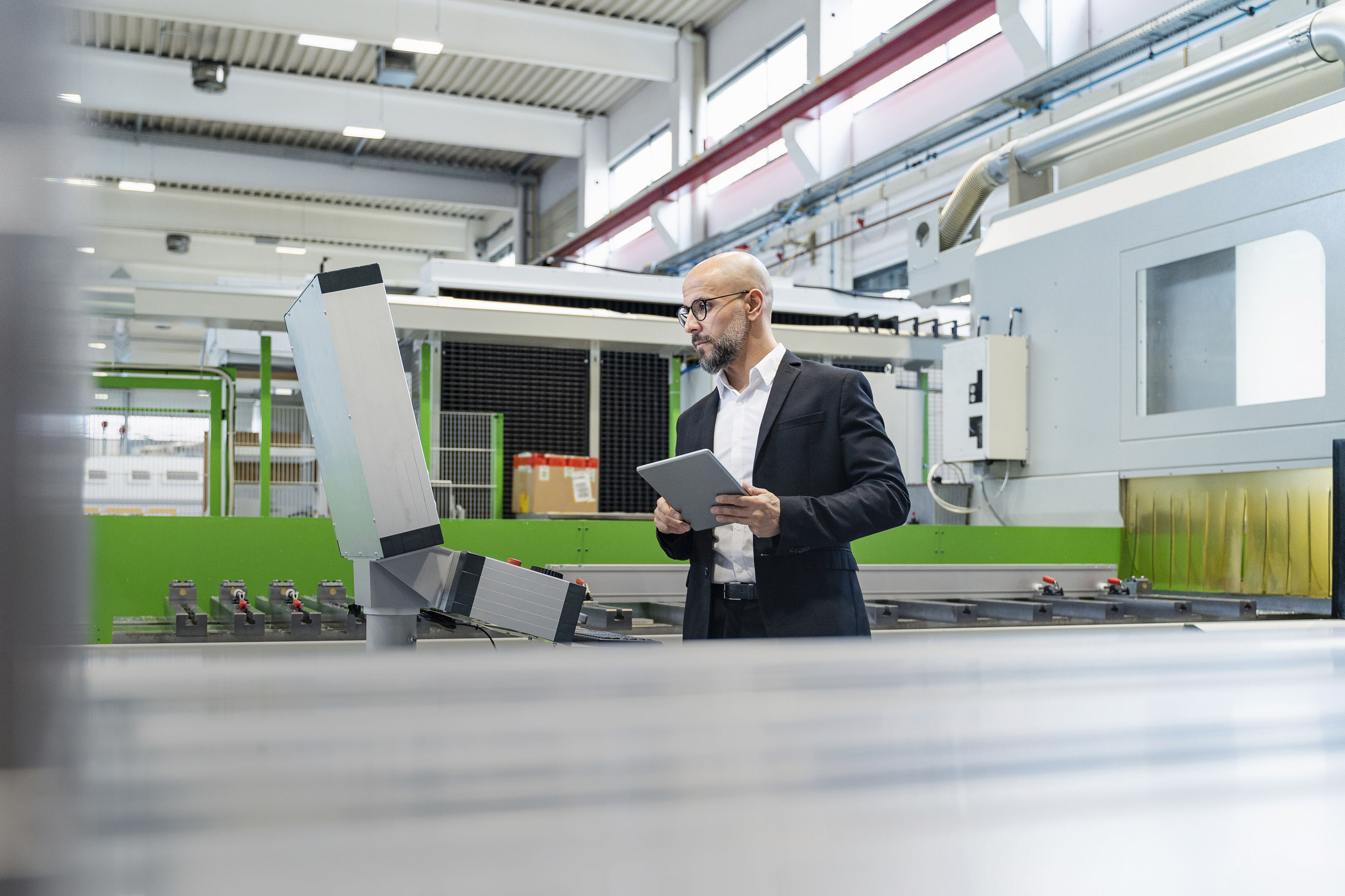 Businessman using tablet at machine in factory